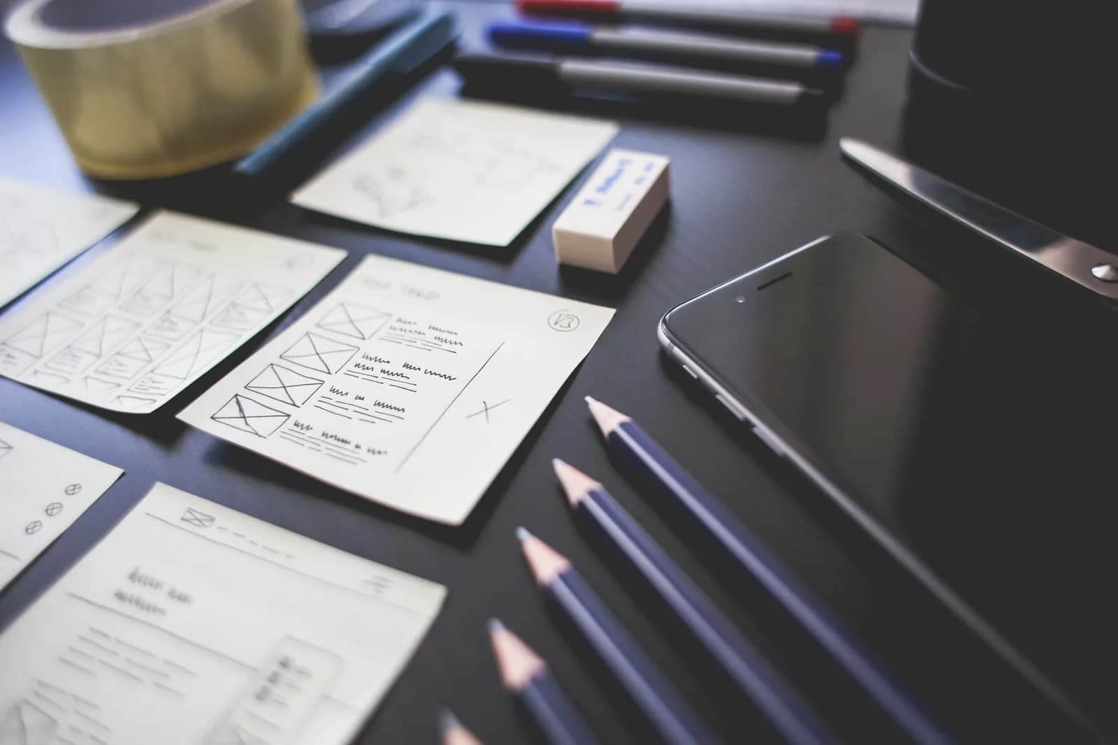 Website interface wireframes and design tools arranged on a desk